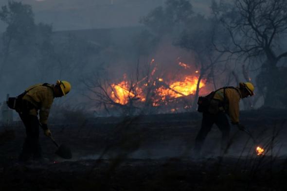 Firefighters work to put out some fire hot spots. Photo by: Mike Blake