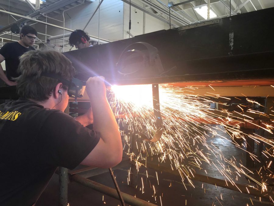 Senior Jefferey Cronin uses a plasma cutter to cut of a piece of steel. Photo by: Kole Petty