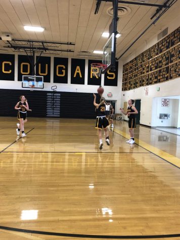 Junior Madeleine Scheer (number 21) went in for a lay up as sophomore Tiernan Philips (number 23, far right) waited to continue the three man weave drill. Photo by Logan Wilkov