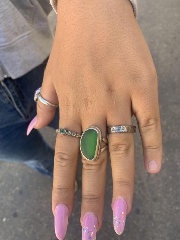 Chloe Cross ‘24 (center) rocks a sea glass ring. Cross said, “My favorite piece is probably my Betty Belts green sea glass ring.” Many students wear meaningful jewelry from family members that hold sentimental value. Cross said,  “My mom bought it for me on my birthday, but it’s also just a really cute statement piece.” Photo by: Ace Rico