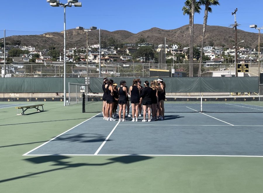 The VHS Girls Tennis Team huddles before the match. Its impressive how well the team gets along. The returning players are very supportive of the new players, and very inclusive. Starter or sub, or developing player, everyone treats each other with kindness and encouragement, said Girls Tennis Coach Alison Ferguson. Photo by: Belen Hibbler
