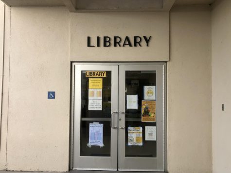 The new library sign above the doors. In the glass window is the old handmade sign by teacher librarian Susan Adamich. Photo by: Kendall Garcia