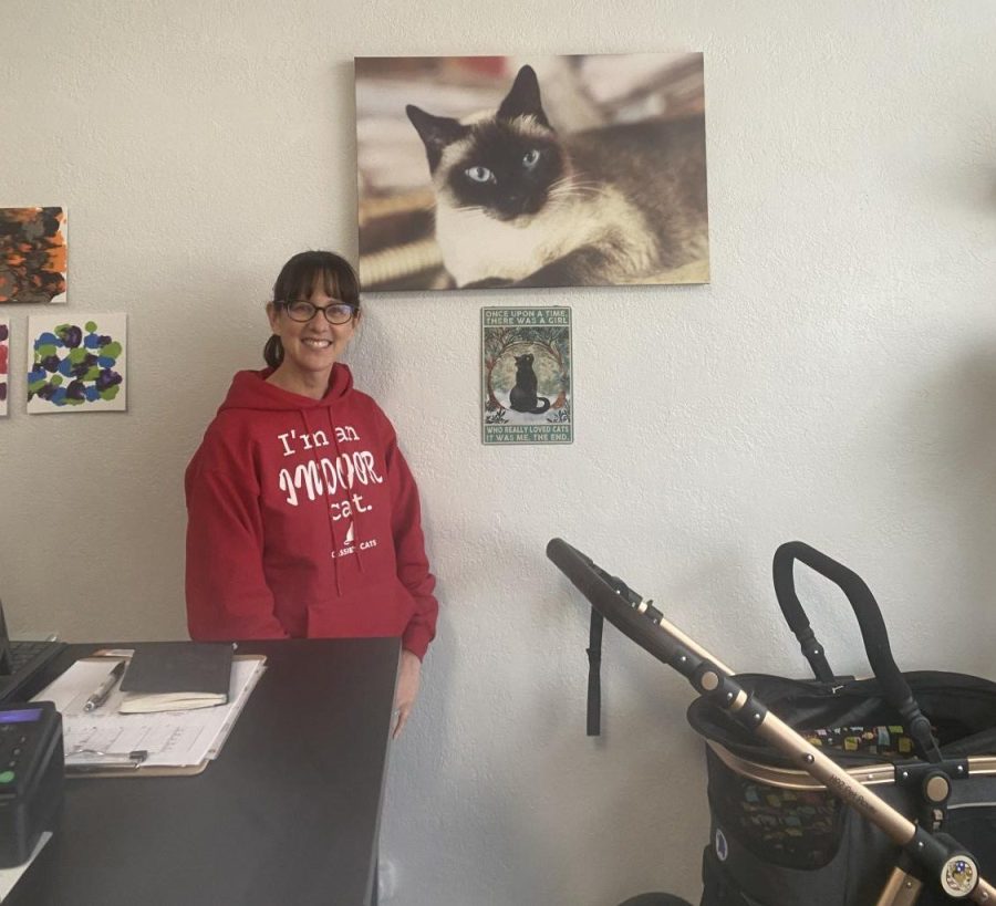 Jennifer Thompson (pictured), the founder of Cassies Cats has been a cat lover her whole life. In the featured image, she is posing with with a portrait of Cassie, her childhood cat. Photo by: Soraya Stegall